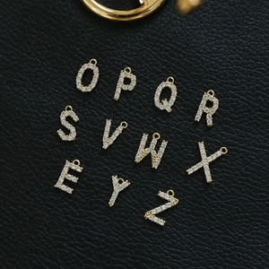 Macro view of gold plated alphabet pendants with cubic zirconia on black leather