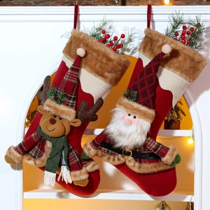 Detail of plush Christmas stockings featuring 3D Santa and reindeer with red plaid fabric