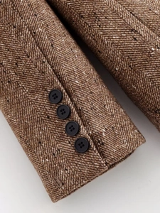 Détail d'une manche en tweed à chevrons avec quatre boutons décoratifs sur blazer brun