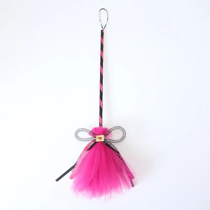 Detail of Halloween witch broom featuring pink tulle, black stripes, and golden buckle