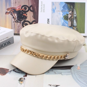 Detail of cream PU leather newsboy cap featuring a decorative gold metal chain on top