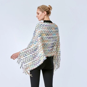 Détail d'un poncho en tricot blanc avec motifs à vagues colorées et glands à franges