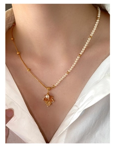 Detail of gold maple leaf pendant necklace featuring split pearl and bead chain design