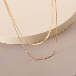 Detail of layered gold snake and box chains showing bright metallic texture