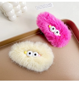 Detail of rose red and beige plush hair clips with big eyes on golden tray decor