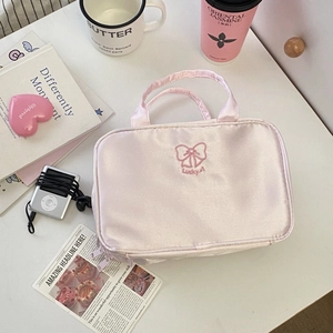 Dettaglio della borsa da trucco in raso rosa con ricamo Lucky e fiocco decorativo
