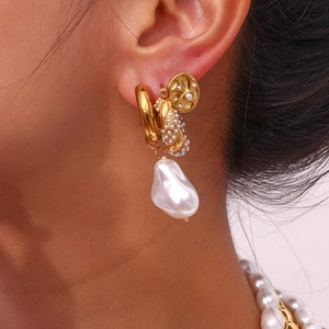 Macro view of gold baroque pearl earrings showing hammered metal texture and glossy finish