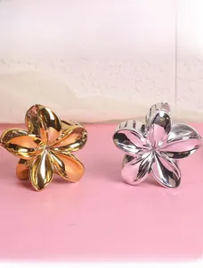 Detailed view of metal flower hair claws in polished gold and silver finishes