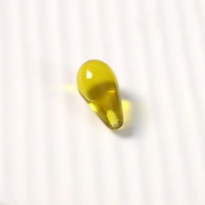 Macro shot of yellow-green transparent teardrop resin beads with smooth glossy finish