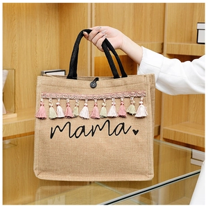 Close-up of linen tote bag featuring mama heart print and colorful hanging tassels