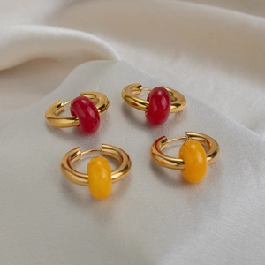 Set of two pairs of gold hoop earrings with red and yellow beads on beige silk fabric