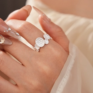 Macro detail of silver ring featuring textured circular discs and intricate relief patterns