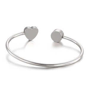 Bracciale rigido argento minimalista con cuore e dettagli geometrici su fondo bianco