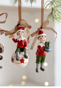 Close-up of resin Christmas elf ornaments with gift boxes hanging on a festive tree
