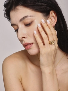 Close-up of vintage hollow gold ring with white stone inlay on model finger