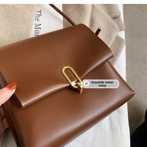 Détail du sac en cuir mat marron foncé avec un fermoir métallique doré en forme de U