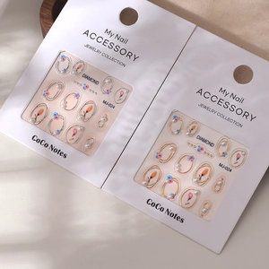 Autocollants nail art avec perles et cadres dorés sur cartes de présentation blanches