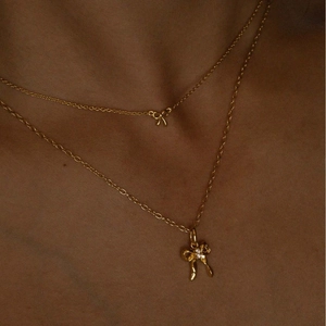 Detail showing two gold bow necklaces with zircon accents worn on a model's neck