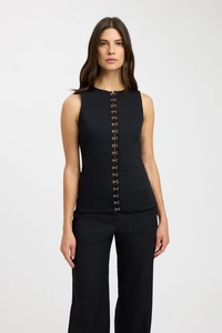 Detail of elegant black sleeveless top with golden hook-and-eye fastenings and straight trousers