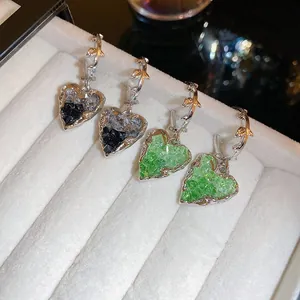 Detail of heart-shaped gradient crystal earrings with thorn design on white velvet box