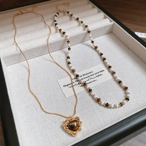 Detailed shot of double-layered heart pendant necklace and vintage beaded chain
