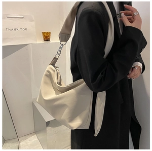 Detail of oatmeal half-moon crossbody bag with metallic chain and wide shoulder strap