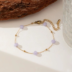Detail of gold stainless steel necklace with lavender flower charms on wood background