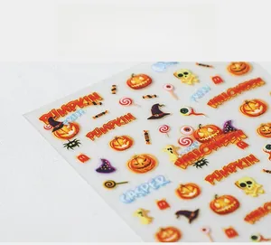 Macro shot of 5D Halloween nail stickers featuring pumpkins, skulls, and ghost patterns