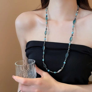 Gros plan d'un collier vintage en perles de pierre naturelle porté par un mannequin