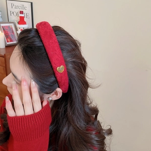 Detail view of red velvet padded headband with heart-shaped golden metal accent on model