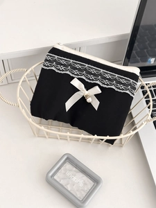 Chic black fabric pouch with white lace, silk bow and pearl pendant in a basket