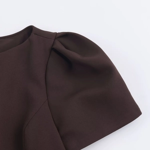 Detailed close-up of crew neck and pleated puff sleeve on brown mini vacation dress