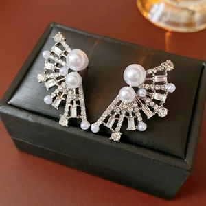 Detailed close-up of fan-shaped silver pearl earrings with crystals on a black leather box