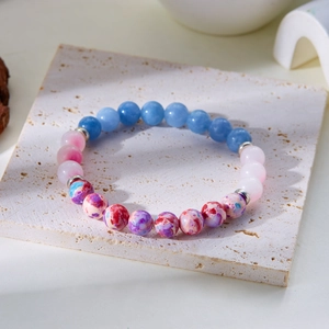 Detailed macro shot of 8mm gradient natural stone beads with silver spacers on travertine