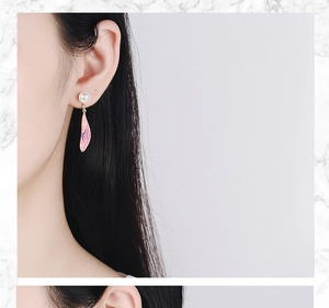 Macro detail of long pearl earrings with pink and purple gradient wing pendants on model