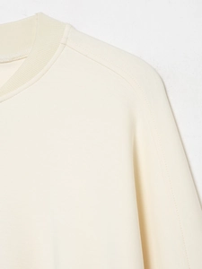 Détail du col rond côtelé et des coutures d'épaule d'un blouson aviateur beige