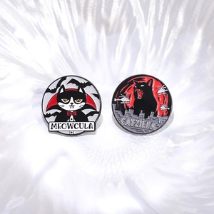 Black enamel pins featuring Meowcula and Catzilla cat designs in dark punk style