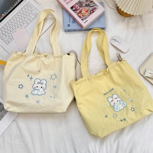 Detail of embroidered canvas tote bags with rabbit patterns and drawstring closure