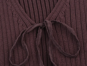 Close-up of deep brown ribbed knit fabric with delicate tie-knot detail on the garment
