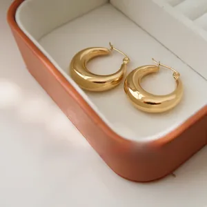 Close-up of chunky gold hoop earrings with polished finish inside a jewelry box