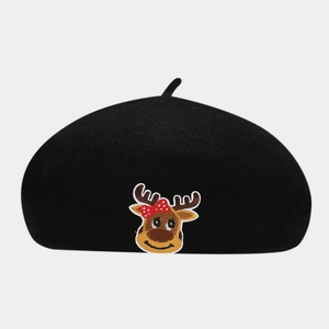 Detail of cartoon reindeer embroidery on a black wool beret with a red polka dot bow