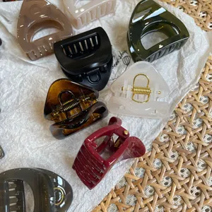 Flat lay of multiple resin hair claws in black, amber, and burgundy with metal springs