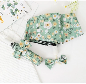 Close-up of mint green floral umbrella with matching case and bow accessory