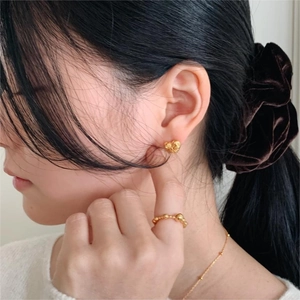 Detailed view of minimalist gold heart stud earrings and beaded ring on model