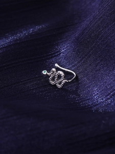 Macro view of silver snake-shaped U-ring with micro-paved green zircon eye detail