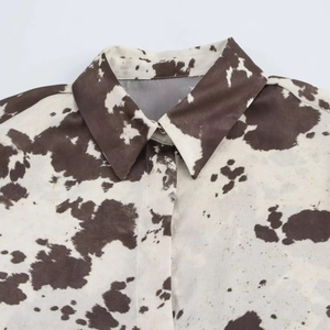 Gros plan détaillé de la chemise à imprimé vache marron et blanc avec col pointu et soie