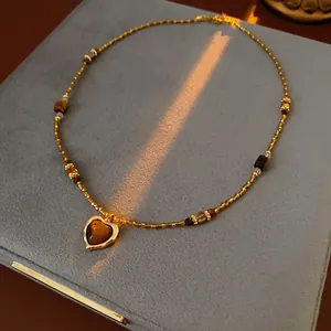 Collier de perles marron vintage avec pendentif coeur sur boîte à bijoux en velours