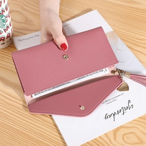 Dusty pink long envelope wallet for women with heart tassel charm on light wood background