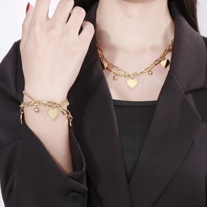 Close-up of layered gold heart pendant necklace and bracelet set on a model