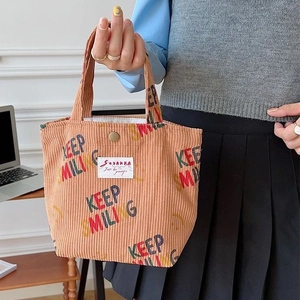 Brown corduroy tote bag with Keep Smiling print and magnetic snap closure held by hand